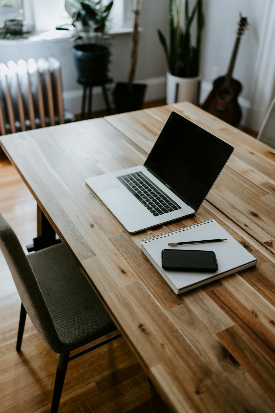 Scrivania minimalista per ufficio domestico con laptop, taccuino e smartphone.